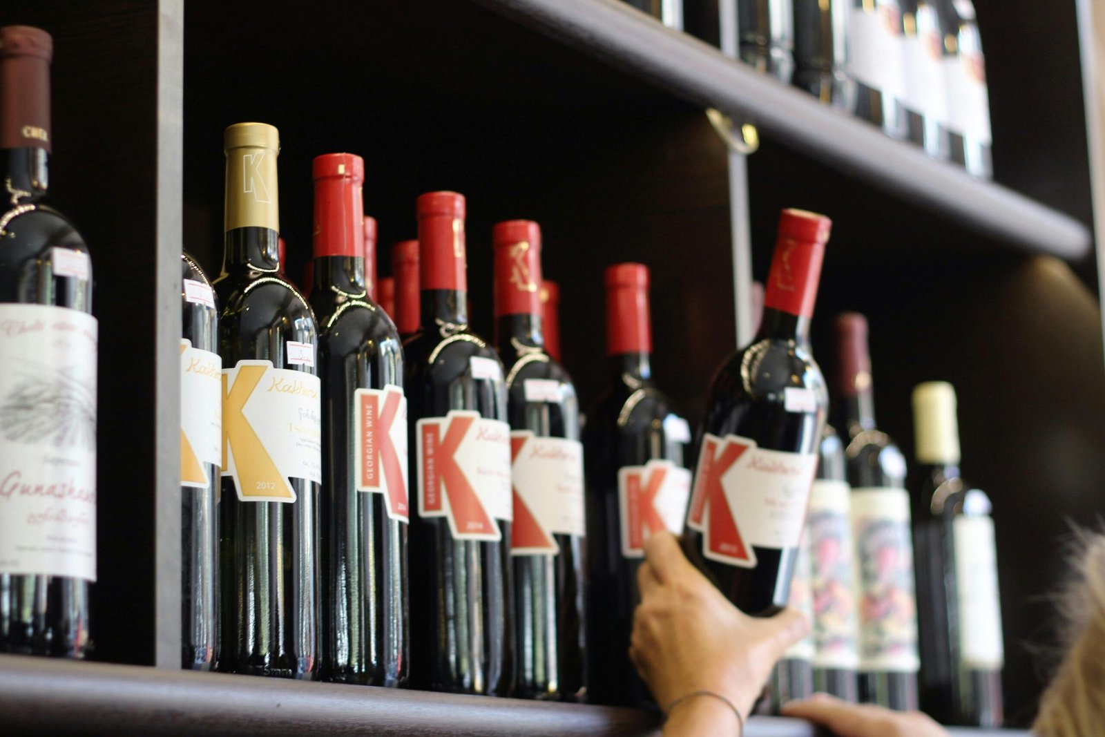 A selection of red wine bottles with bold labels on a store shelf.