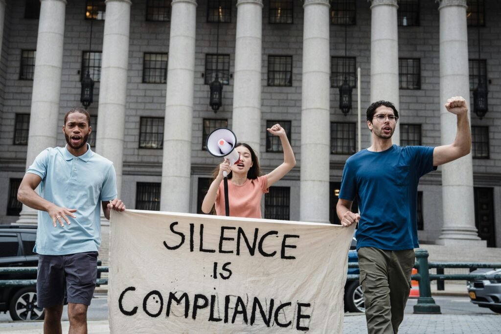 A diverse group of protesters holding a banner advocating change in front of a government building.